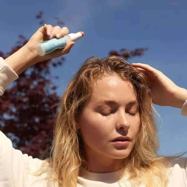 woman spraying Showerless Shampoo on her hair