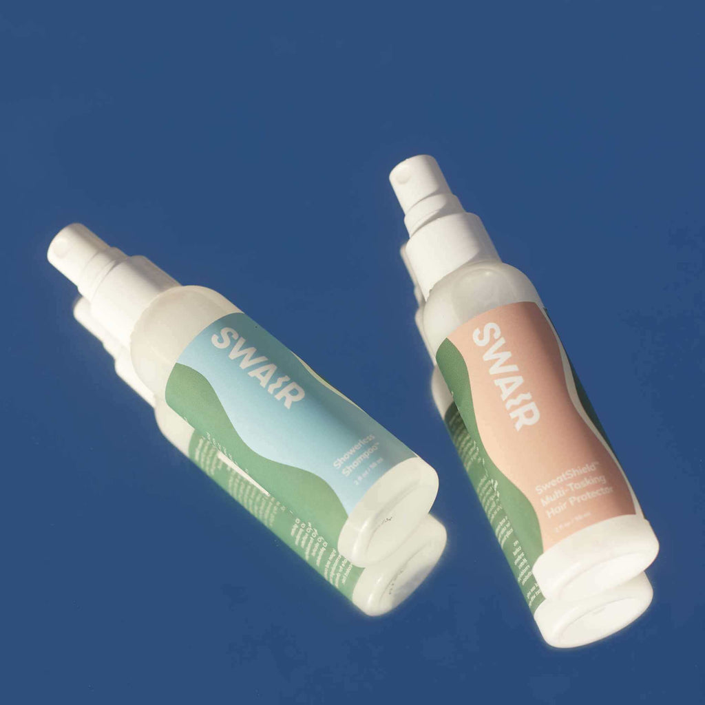 travel size Showerless Shampoo bottle and travel size SweatShield bottle on blue background